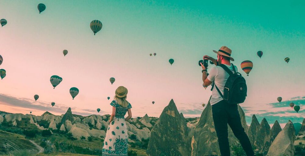 man taking photo of hot air balloons