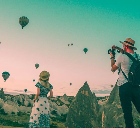 man taking photo of hot air balloons