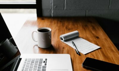 MacBook Pro, white ceramic mug,and black smartphone on table