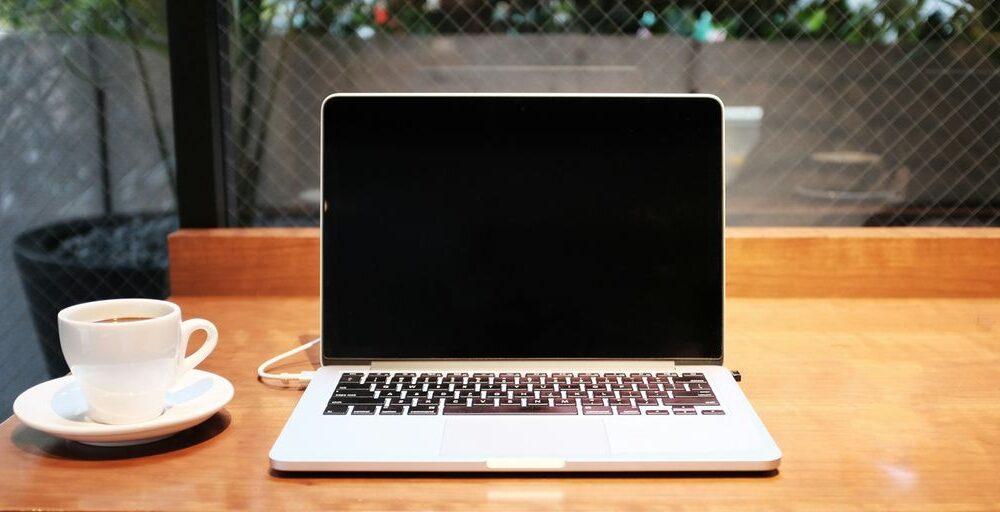laptop computer beside coffee mug
