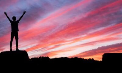 silhouette of man standing on high ground under red and blue skies