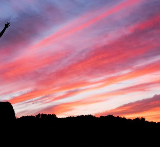 silhouette of man standing on high ground under red and blue skies