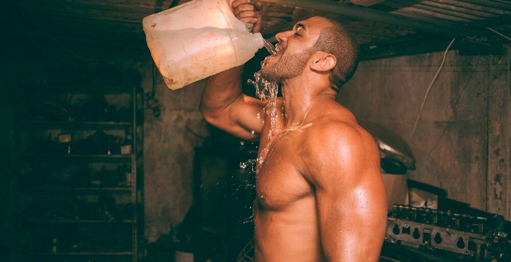topless man drinking water from plastic container