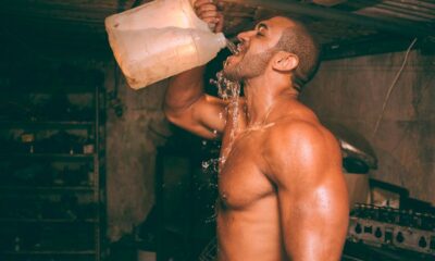 topless man drinking water from plastic container