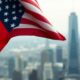 U.S. and Chinese flags intertwined on a city skyline background.