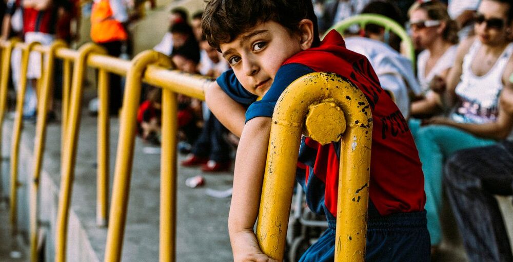 boy in blue and red shirt holding yellow metal bar