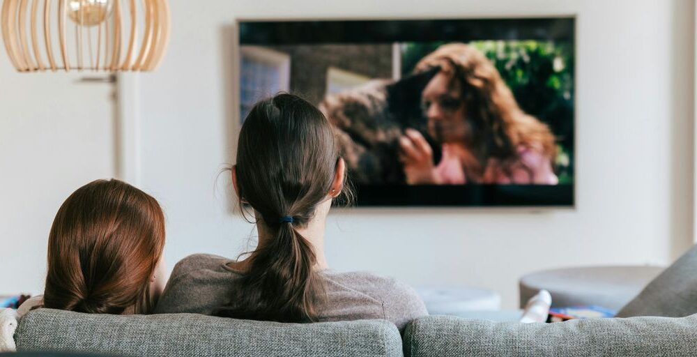 a couple of women sitting on top of a couch