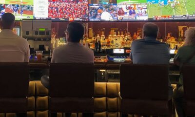 a group of people sitting at a bar watching tv
