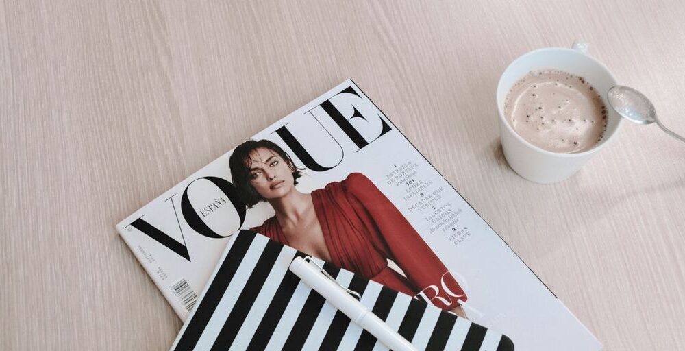 white capped pen on top of Vogue magazine beside cup of coffee