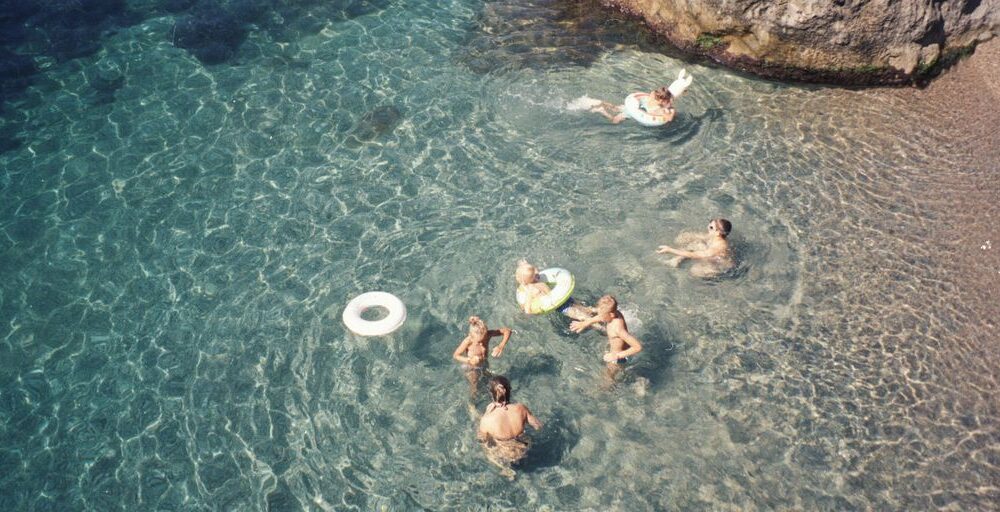 people swimming on body of water during daytime