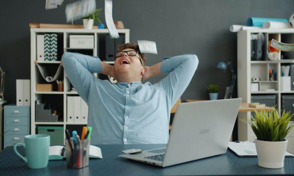 Man celebrating success by throwing papers in office