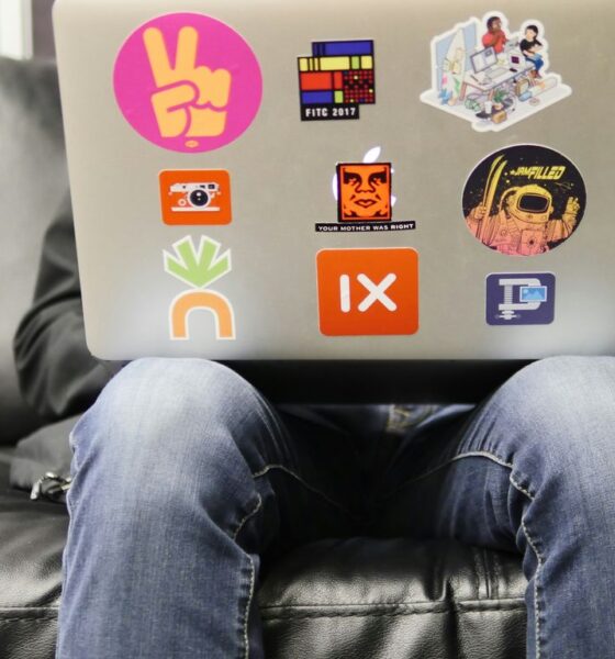 man using silver MacBook sitting on black leather sofa