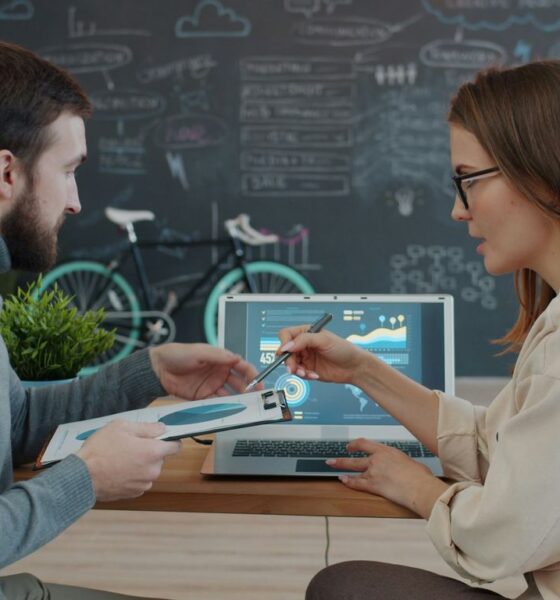 Two colleagues reviewing data on a laptop.
